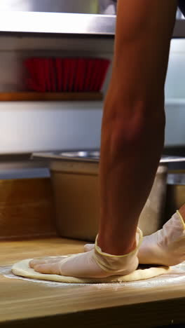 professional chef kneading floured dough for bread in bakery shop. man`s hands are forming the dough on a floured surface and kneading it with his hands. vertical video