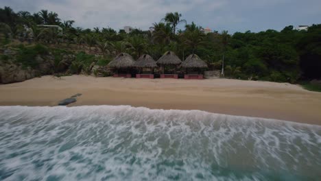 Vista-Aérea-De-Algunas-Cabañas-Y-Olas-Rompiendo-En-Las-Playas-De-Huatulco