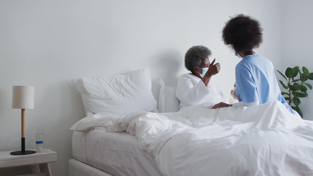 African american female doctor and senior female patient in face masks