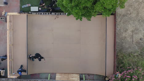 patinadores en mini rampa casera en el patio trasero, vista aérea de arriba hacia abajo