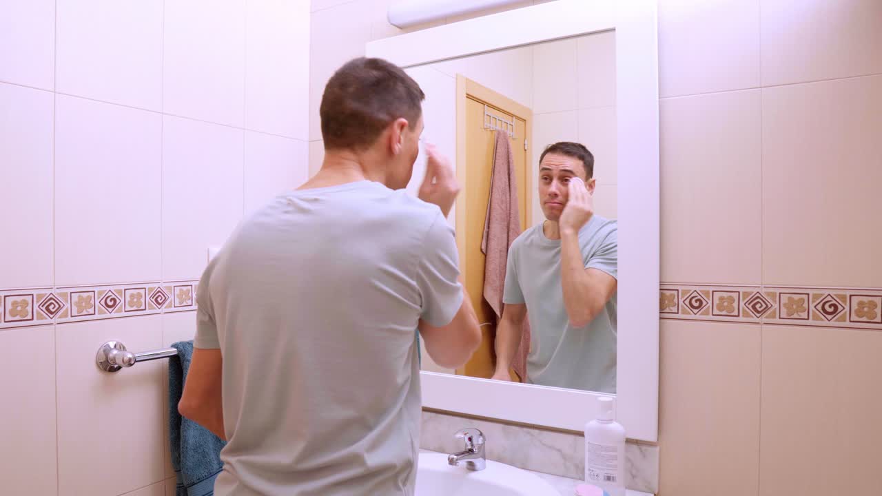 Man practicing facial cleansing routine in modern bathroom