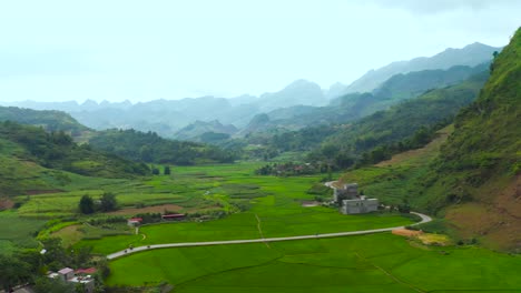 aerial pan left revealing lush rice farms nestled in a misty valley in northern vietnam