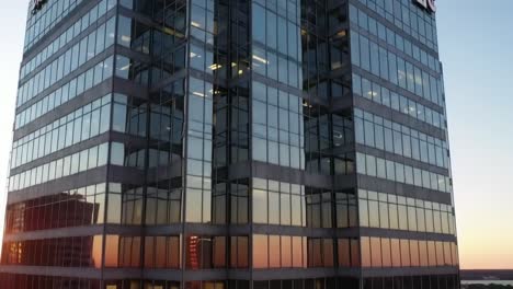 a captivating view of a modern office building as the sun sets, casting vibrant colors across the glass facade. the scene captures the beauty of urban architecture at dusk.