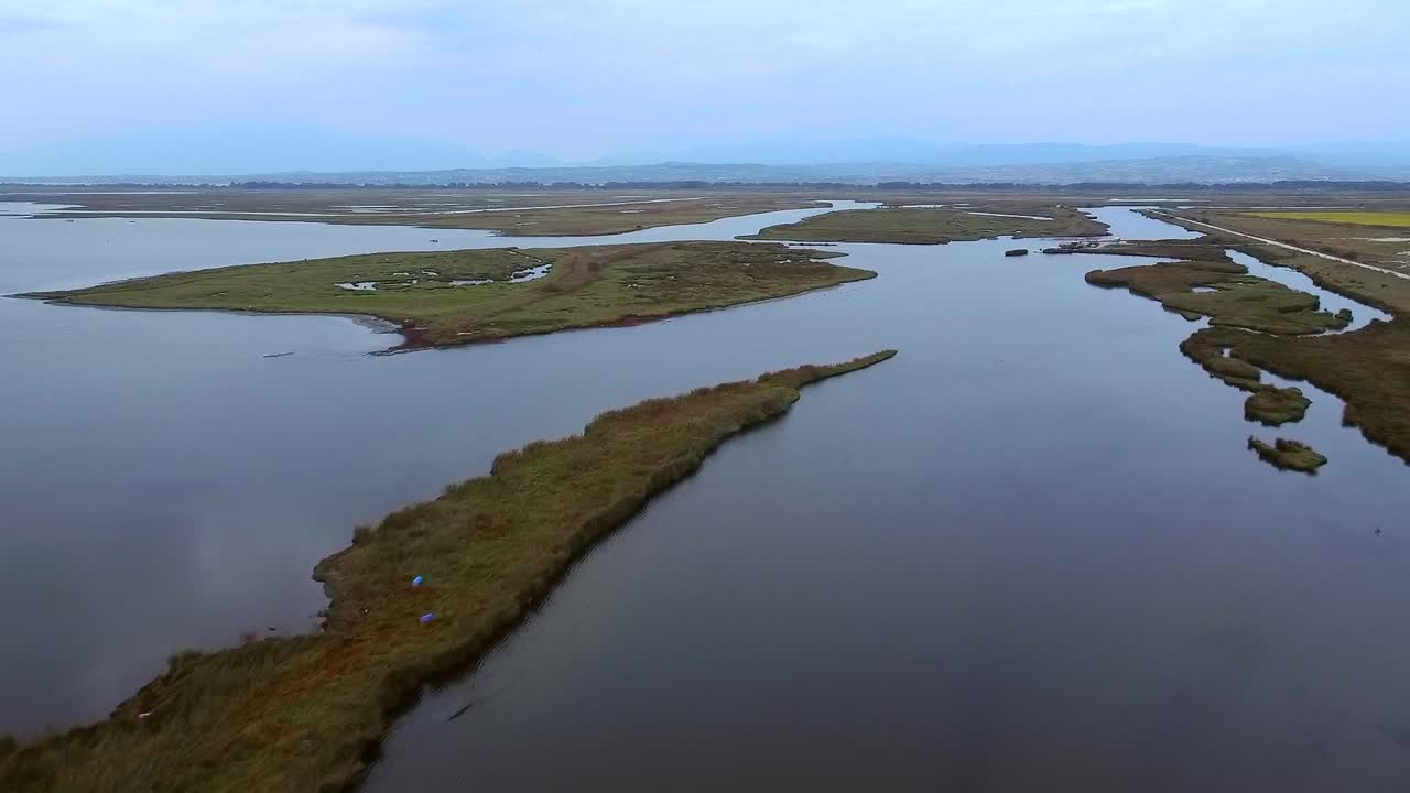 fotografía aérea de aves del parque nacional del delta de los axios con islas verdes, pantanos y lagos durante un día nublado, grecia
