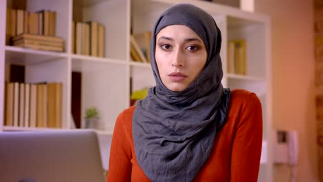 closeup shoot of young attractive muslim female employee typing on the laptop looking at camera indoors in the office