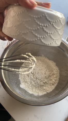 Vertical-video-of-flour-being-poured-into-a-silver-bowl-to-make-vegan-donuts