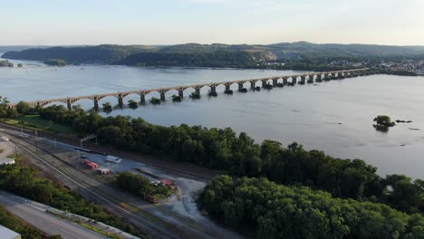 industrial railroad yard and train tracks border majestic susquehanna river, high aerial revealing