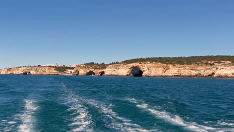 Una-Toma-De-4k-En-Una-Lancha-Rápida-En-Movimiento-Que-Sale-De-Las-Cuevas-Y-Acantilados-De-Benggil-Algarve-Portugal