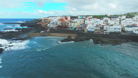 cinematic and orbital aerial view over the beach and coast of el puertillo in the north of the island of gran canaria and with large waves hitting the coast