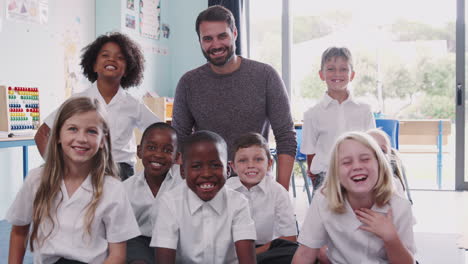 Portrait-Of-Elementary-School-Pupils-Wearing-Uniform-In-Classroom-With-Female-Teacher