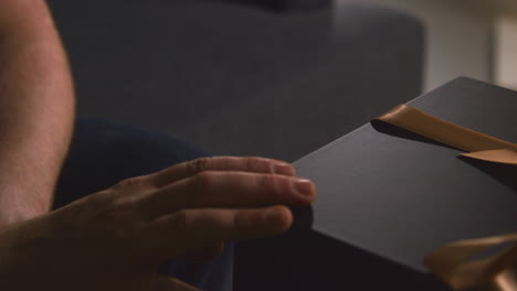 close up of man picking up gift wrapped present from table in lounge at home 2