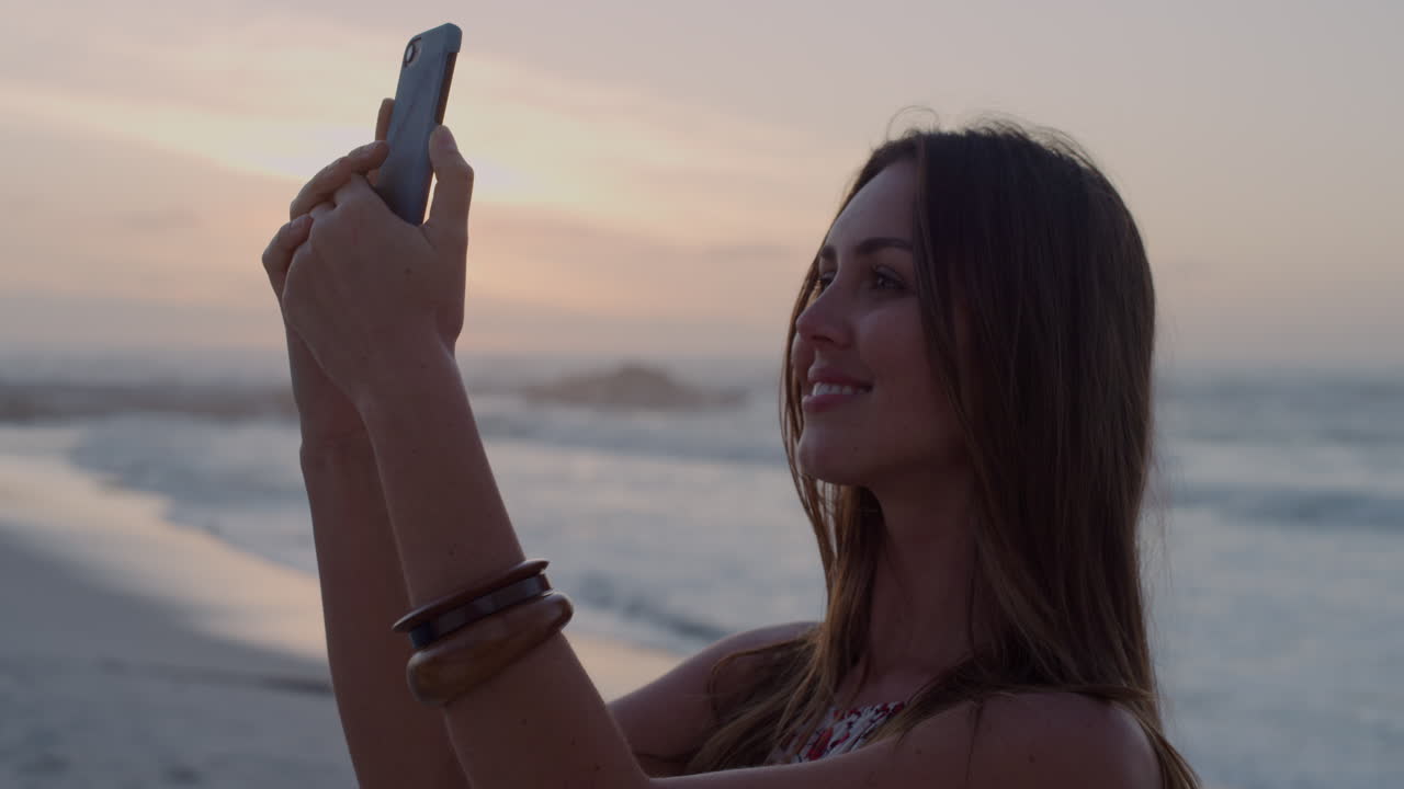 retrato de una joven caucásica usando un teléfono inteligente tomando una foto selfie en una hermosa playa tranquila al atardecer estilo de vida de viaje
