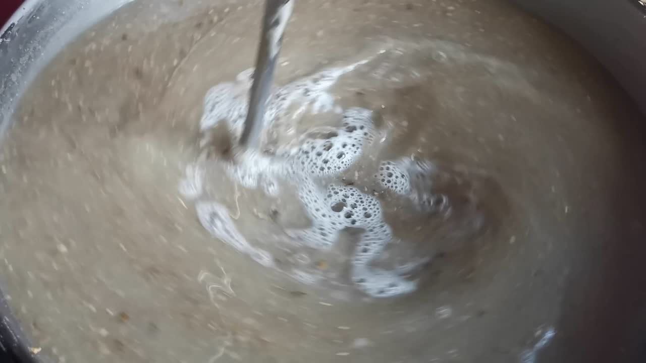Orzo maltato miscelato con acqua, riscaldato e mescolato prima che il lungo cucchiaio venga estratto