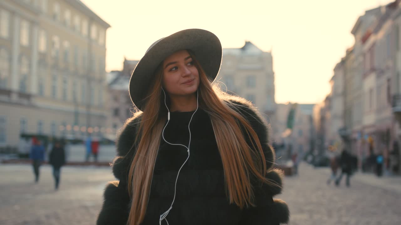 Ragazza giovane che va in città e ascolta musica al telefono