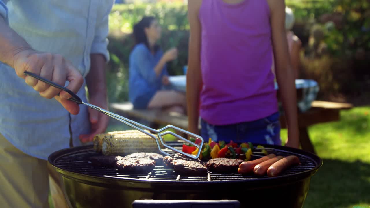 Grandfather and granddaughter preparing barbecue while family having meal 4k