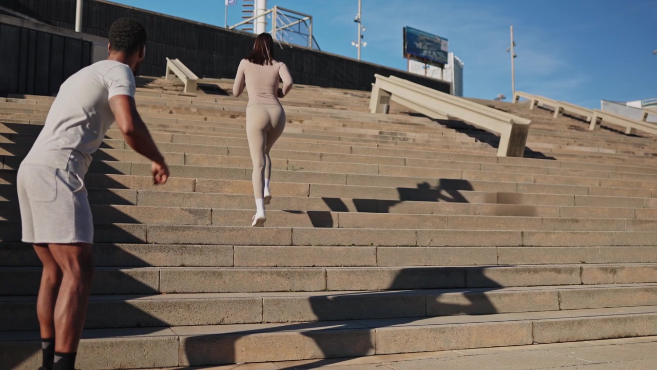 Personal trainer che incoraggia una donna a correre su per le scale all'aperto