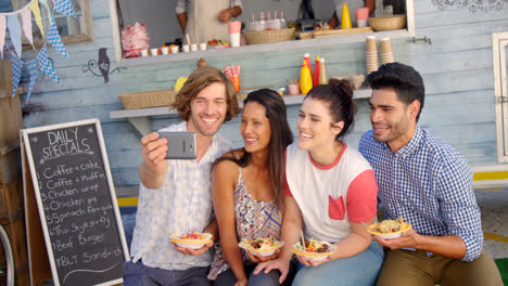 Amigos-Tomando-Selfie-Desde-Un-Teléfono-Móvil-En-Una-Furgoneta-De-Comida