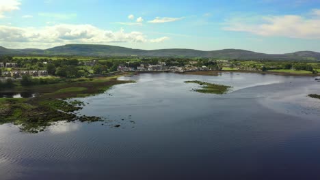 kinvara, galway, irlanda, agosto de 2020, drone volando sobre el agua mientras empuja hacia el pueblo de pescadores