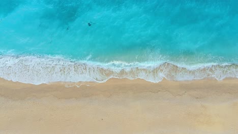 serene aerial view of myrtos beach, kefalonia, showing pristine azure waters and white pebble shores surrounded by lush greenery under a brilliant sunny sky.