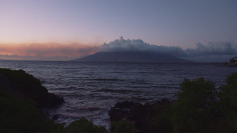 beautiful view of west maui mountains from rocky shore on a cloudy day