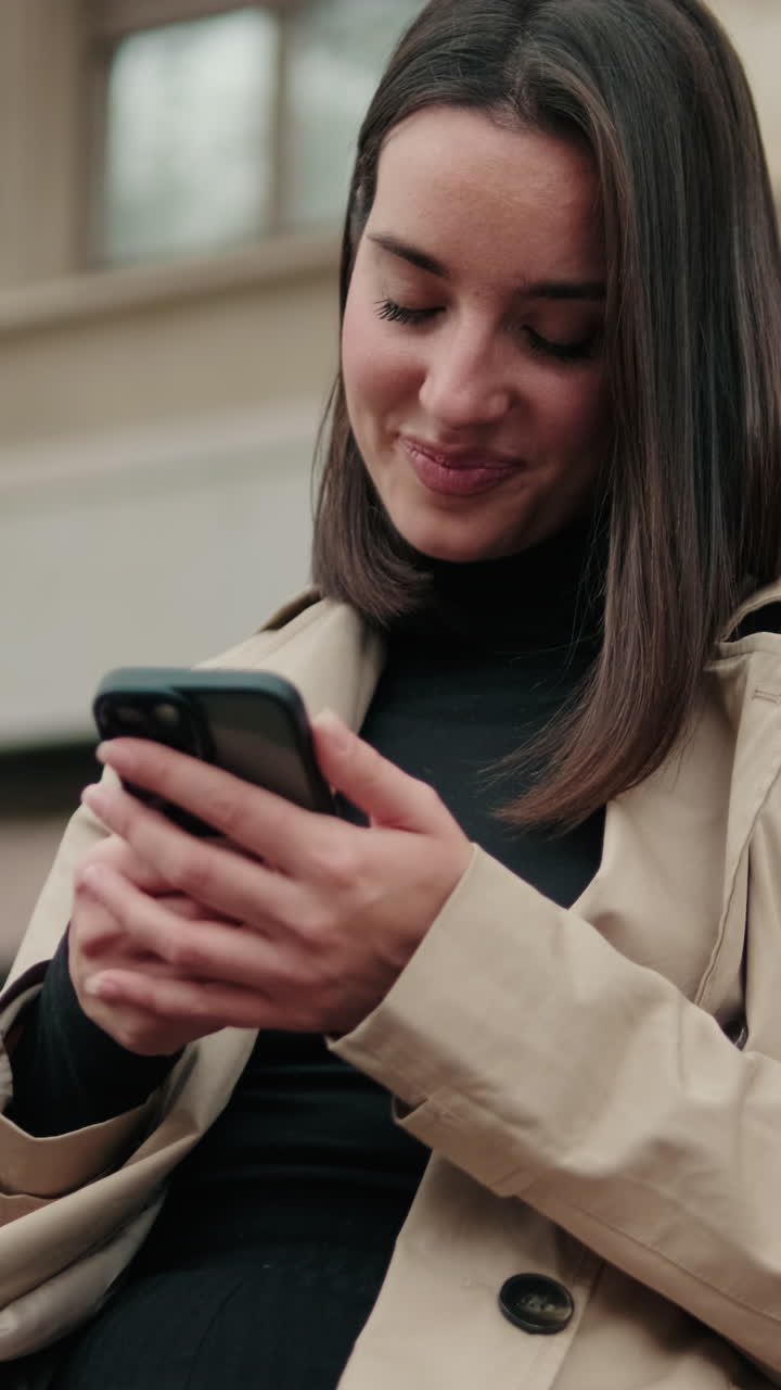 Giovane donna sorridente mentre usa lo smartphone all'aperto