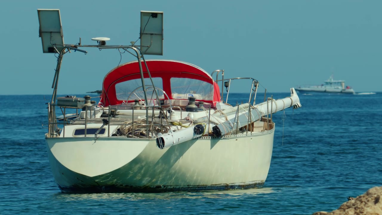 Barca a vela ancorata in un mare blu calmo con pannelli solari che catturano energia, offrendo avventura sostenibile e tranquilla solitudine
