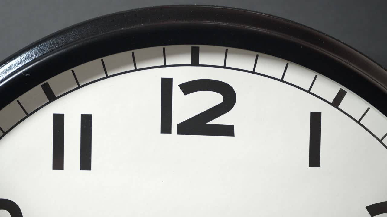 White Clock Face Close Up in Time Lapse on Dark Grey Wall