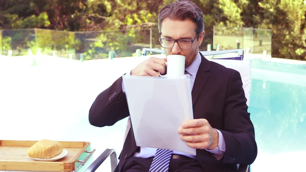 hombre de negocios guapo bebiendo café y leyendo documentos