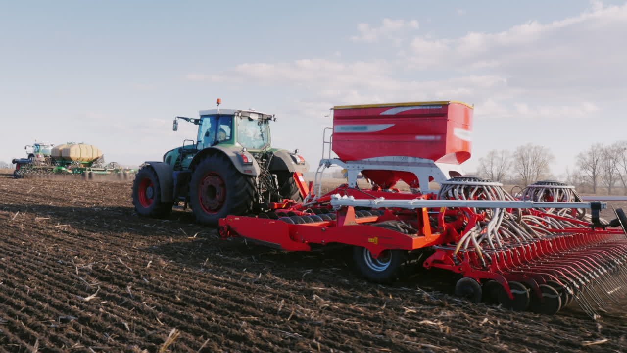 toma de steadicam: dos tractores con sembradoras siembran trigo en el campo a principios de la primavera 2