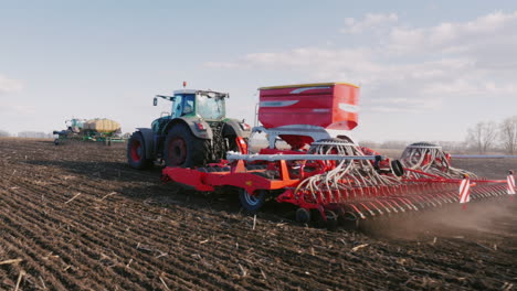 toma de steadicam: dos tractores con sembradoras siembran trigo en el campo a principios de la primavera 2
