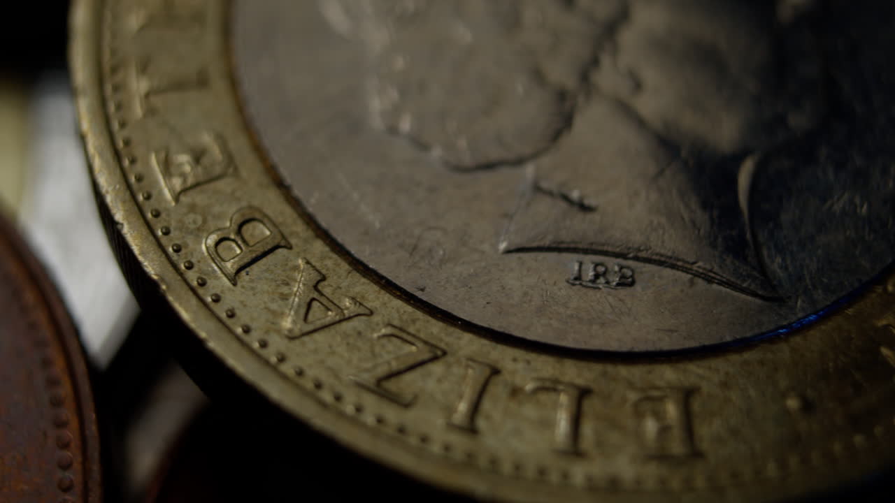 Detailed macro view of a British pound coin showing engraved letters and textures under moody lighting