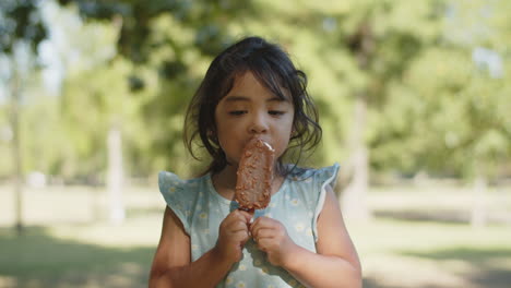 portrait of cute little asian girl eating chocolate ice cream at the park