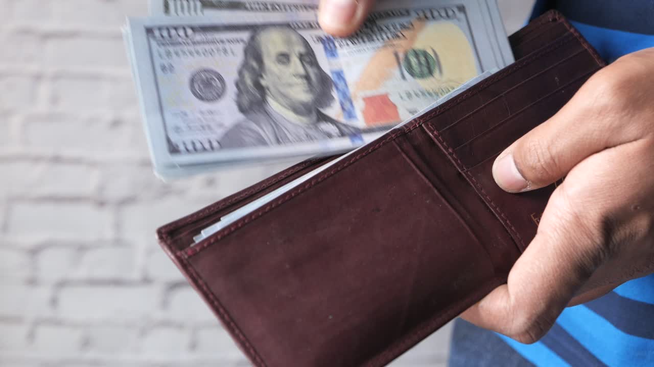 Person holding a wallet with US dollars