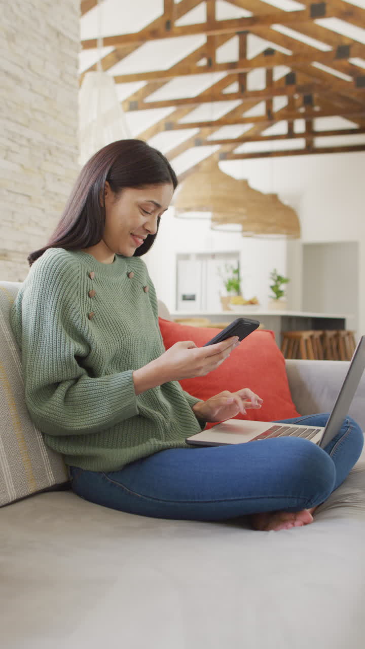 Vertical video of biracial woman using smartphone and smiling