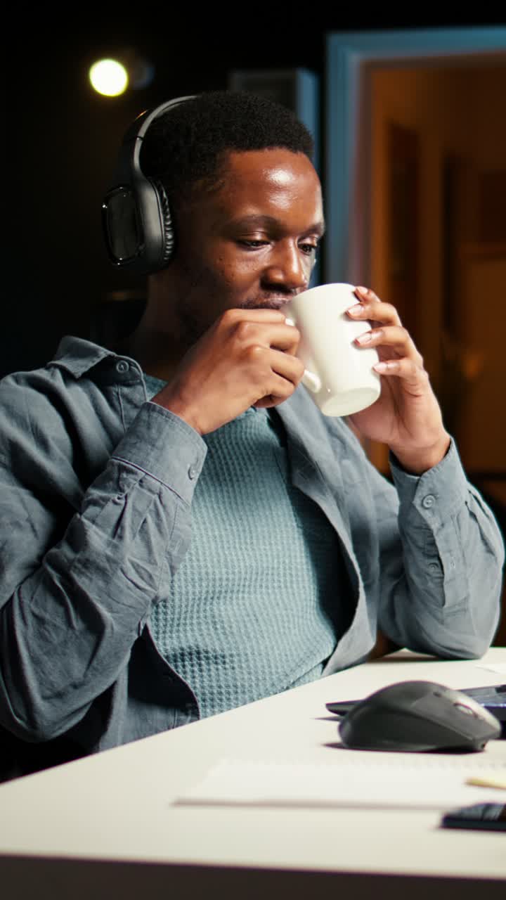 Man working at desk with headphones and mug