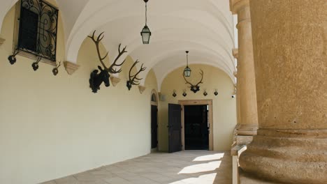 arched hallway in trakošćan castle hunting hall with antler trophies and iron lanterns, croatia
