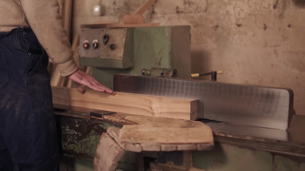 крупным планом кадры мужчины в рабочей одежде, работающего на электропиле с деревянным материалом в столярном деле