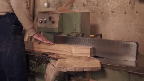 imágenes de primer plano de un hombre vestido con ropa de trabajo trabajando en una sierra eléctrica con material de madera en carpintería