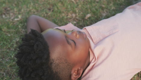 lying on grass, african american boy relaxing outdoors and enjoying peaceful moment