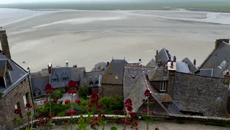 vista panorámica de arriba hacia abajo que muestra el viejo techo de los edificios en la parte superior de la catedral de le mont saint michel durante la marea baja en francia