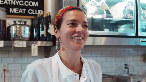 happy young woman laughing behind the counter at a delicatessen