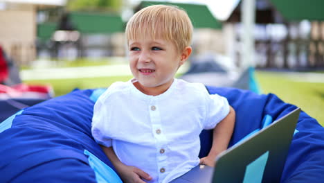 young boy using laptop outdoors