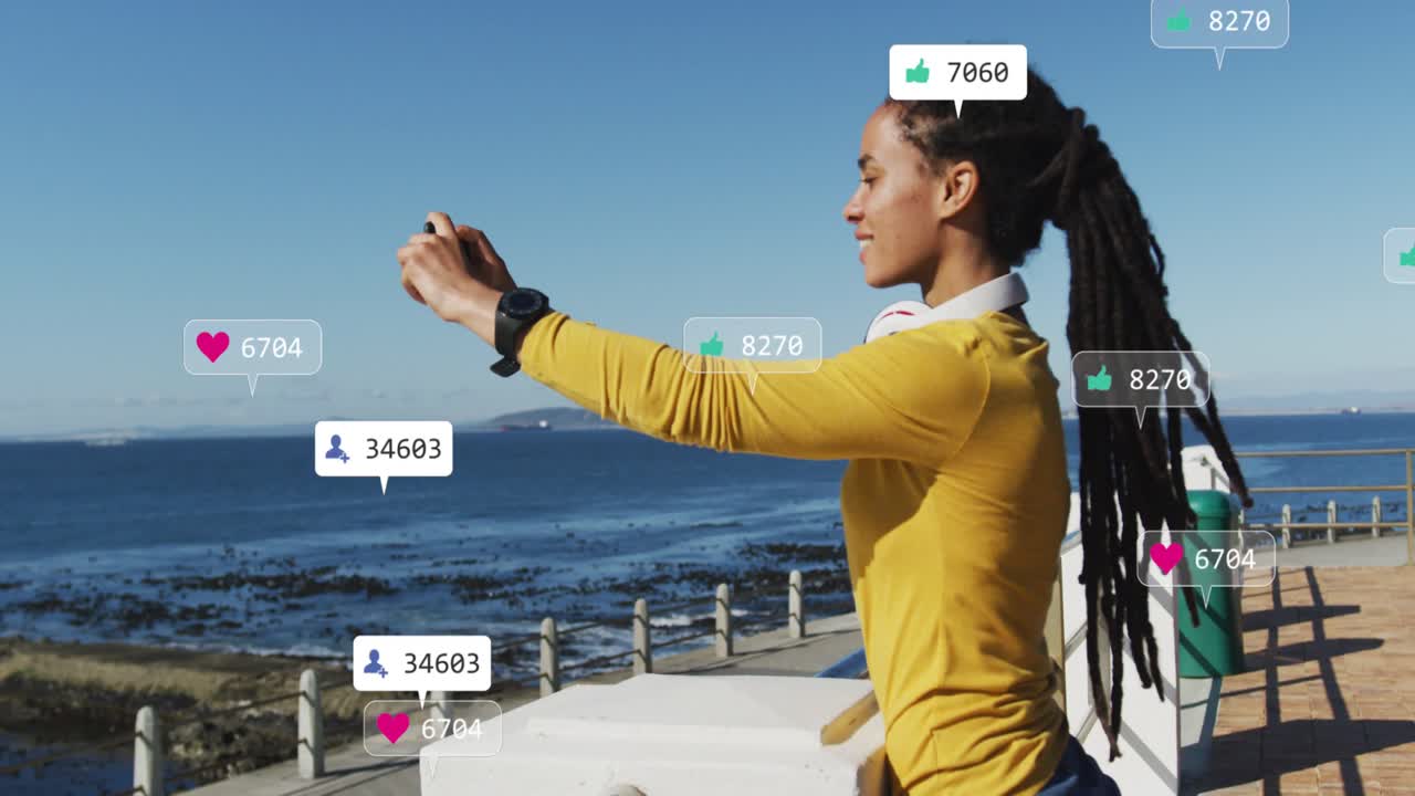 Woman holding phone on seaside framing shot and causing social alerts near screen as checking likes