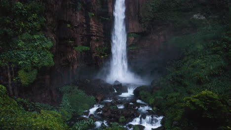 Flying-backwards-from-the-Blue-Cotton-Waterfall,-in-East-Java,-Indonesia---reverse,-drone-shot