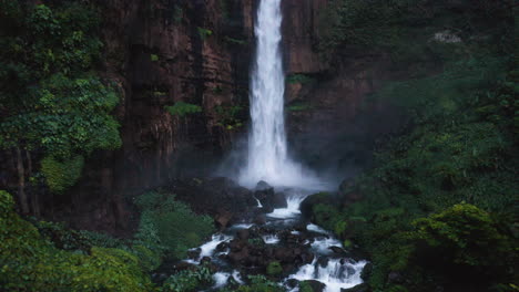 flying backwards from the blue cotton waterfall, in east java, indonesia - reverse, drone shot