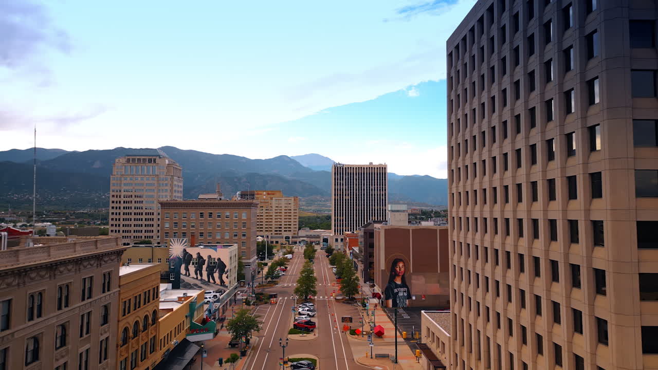 Colorado Springs, USA, 22 July 2025: Flight over the wide street with cars parked. Approaching the buildings with murals in the cityscape of Colorado Springs, Colorado, USA