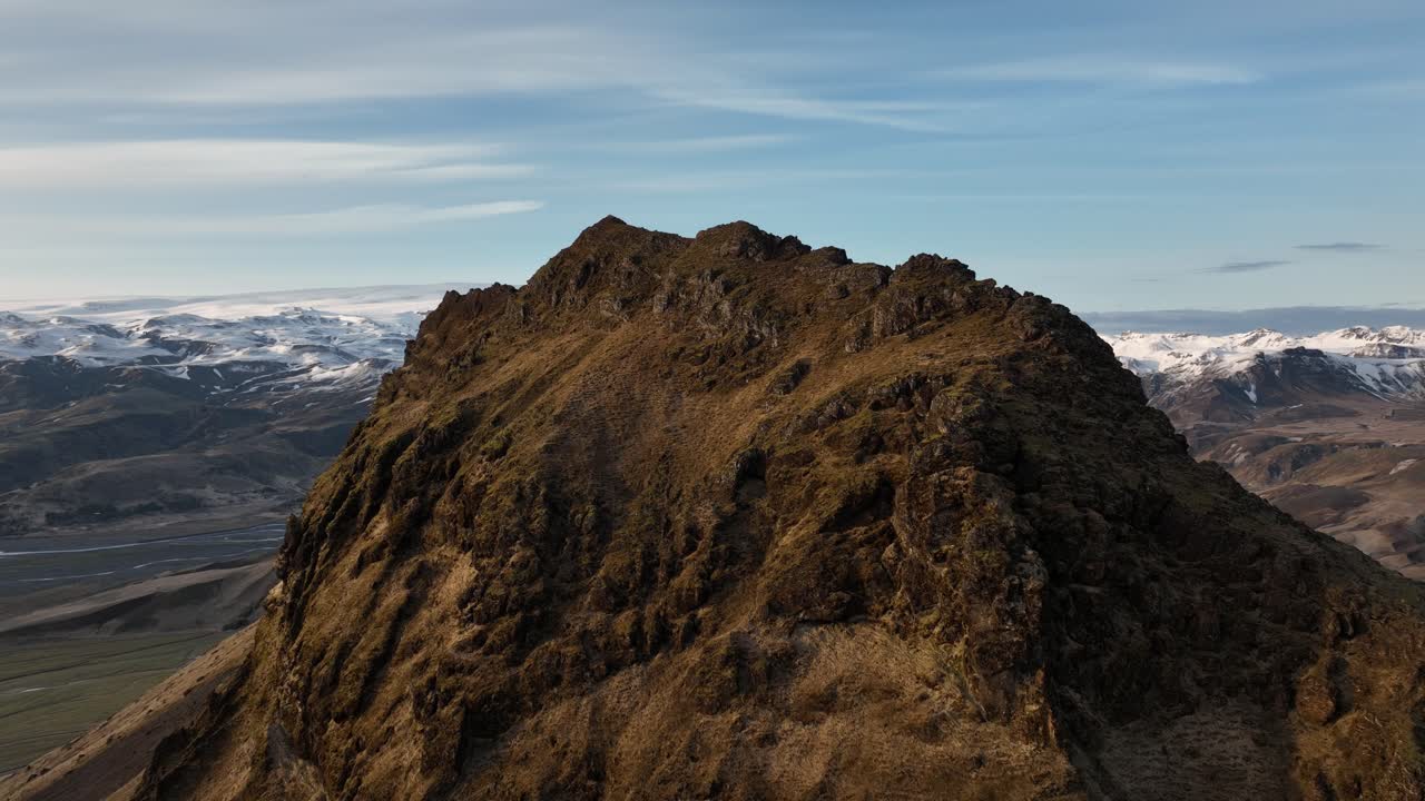 fotografía de un avión no tripulado de un escarpado pico rocoso en búrfell, islandia, con distantes montañas y valles cubiertos de nieve que crean un paisaje natural dramático