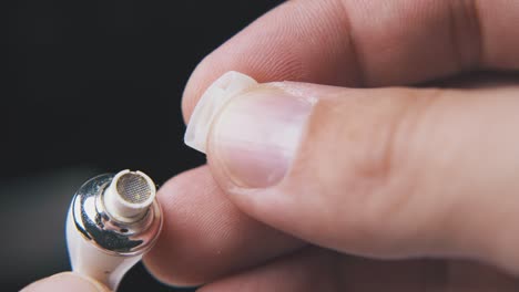 man takes off silicone cup from earphone on black background