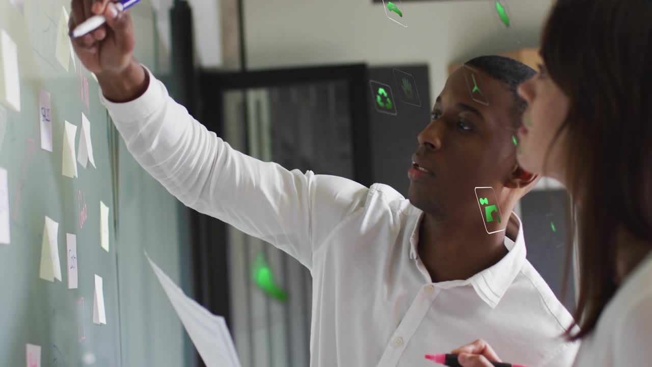 Man reviewing brief, raising marker and marking glass wall with sticky notes for business planning