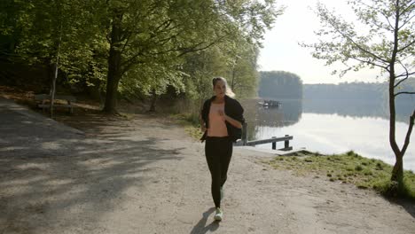 Woman-running-next-to-lake-on-sunny-day